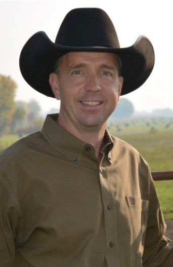 Man in cowboy hat smiling outdoors