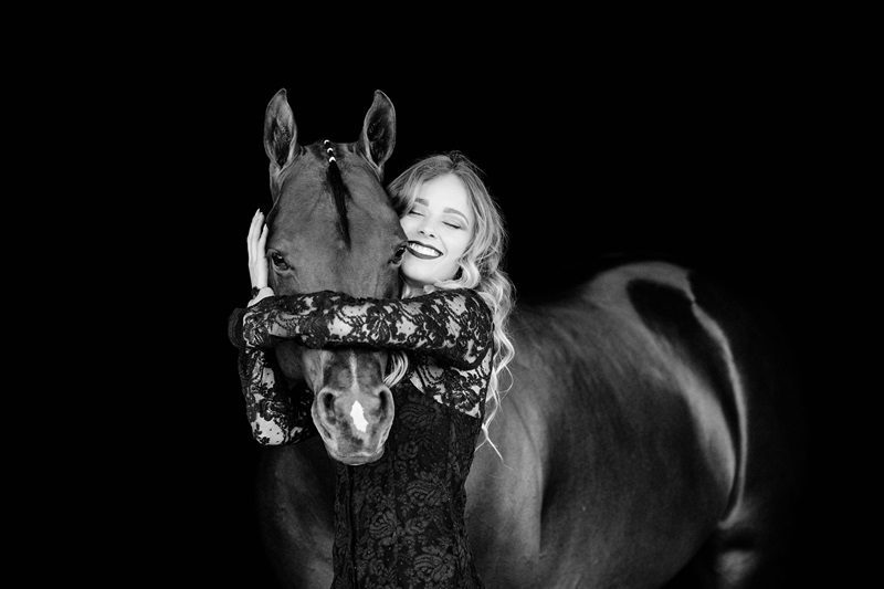 Lace-clad woman hugging horse, monochrome