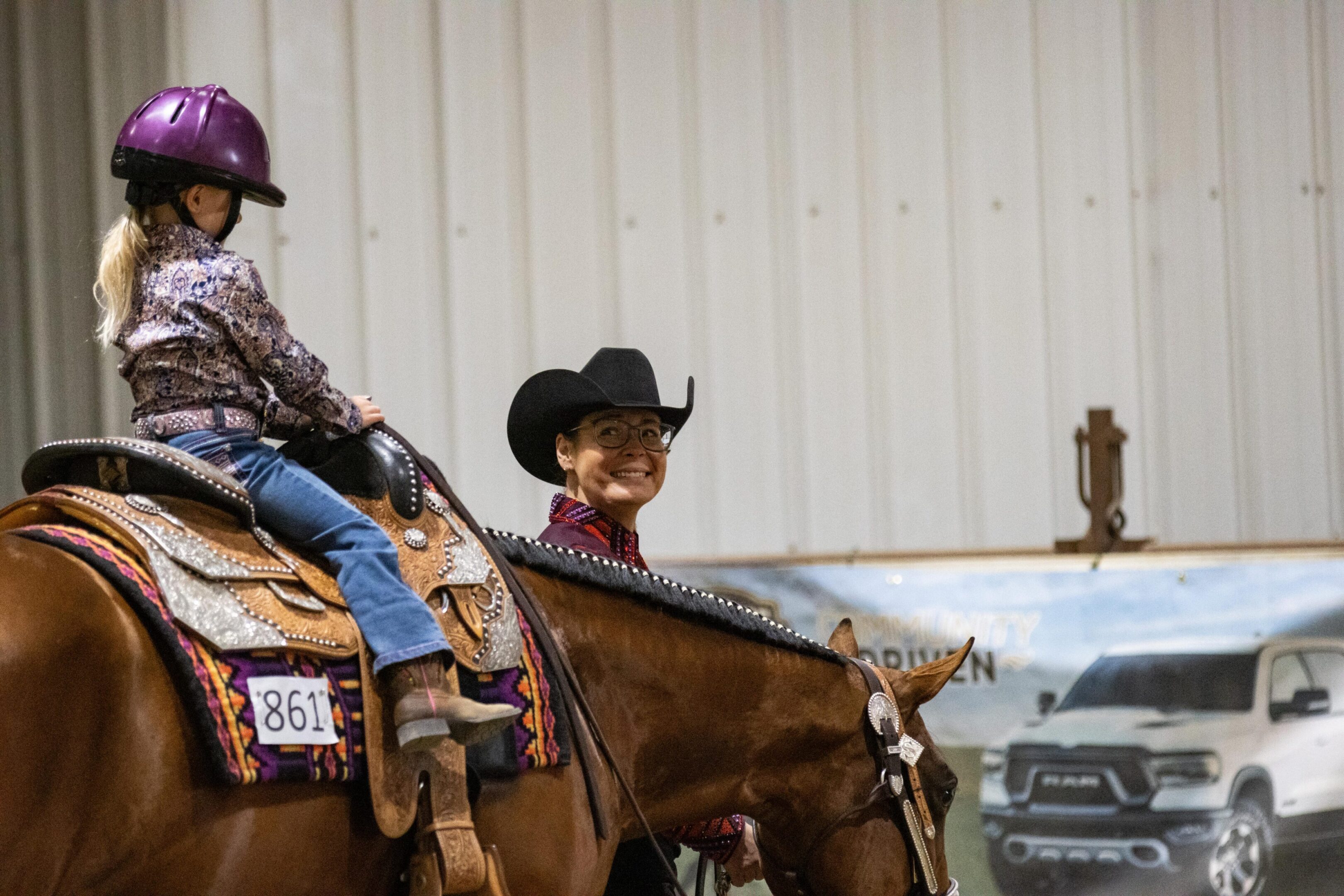 Girl in purple helmet riding beside smiling rider