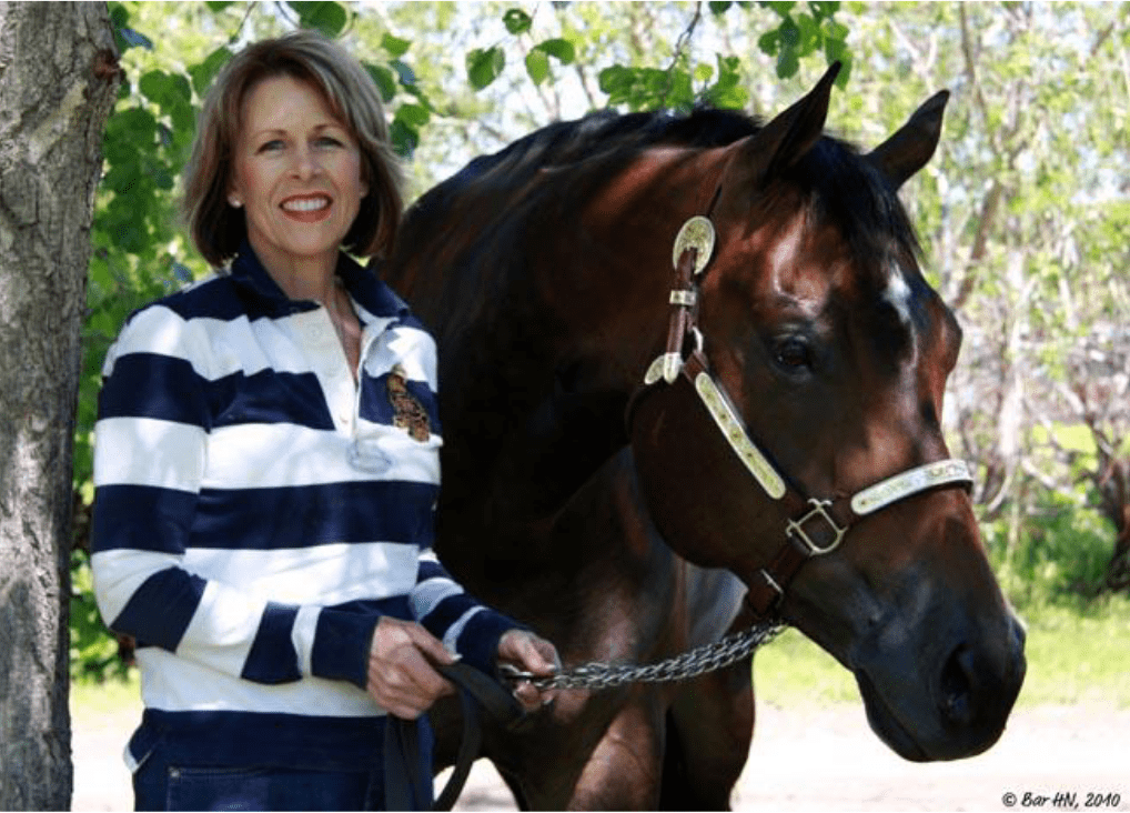 Smiling woman holding horse reins outdoors