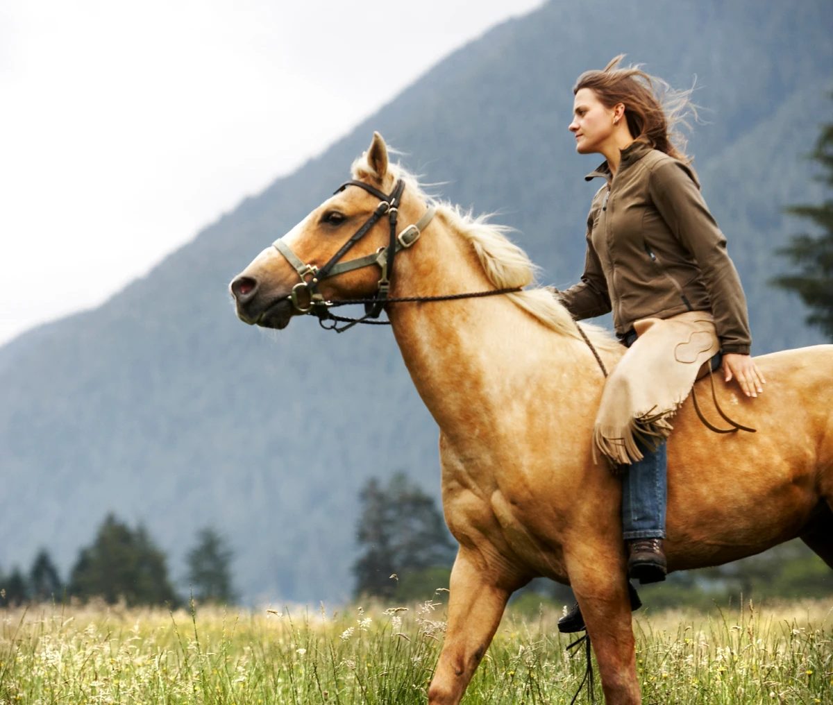Woman riding horse in mountain landscape