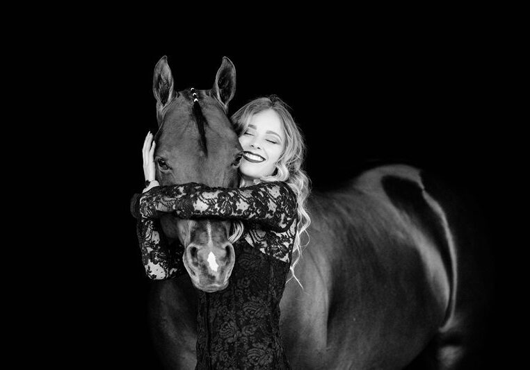 Lace-clad woman hugging horse, monochrome