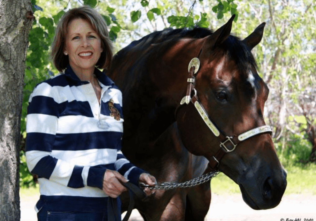 Smiling woman holding horse reins outdoors