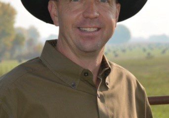 Man in cowboy hat smiling outdoors